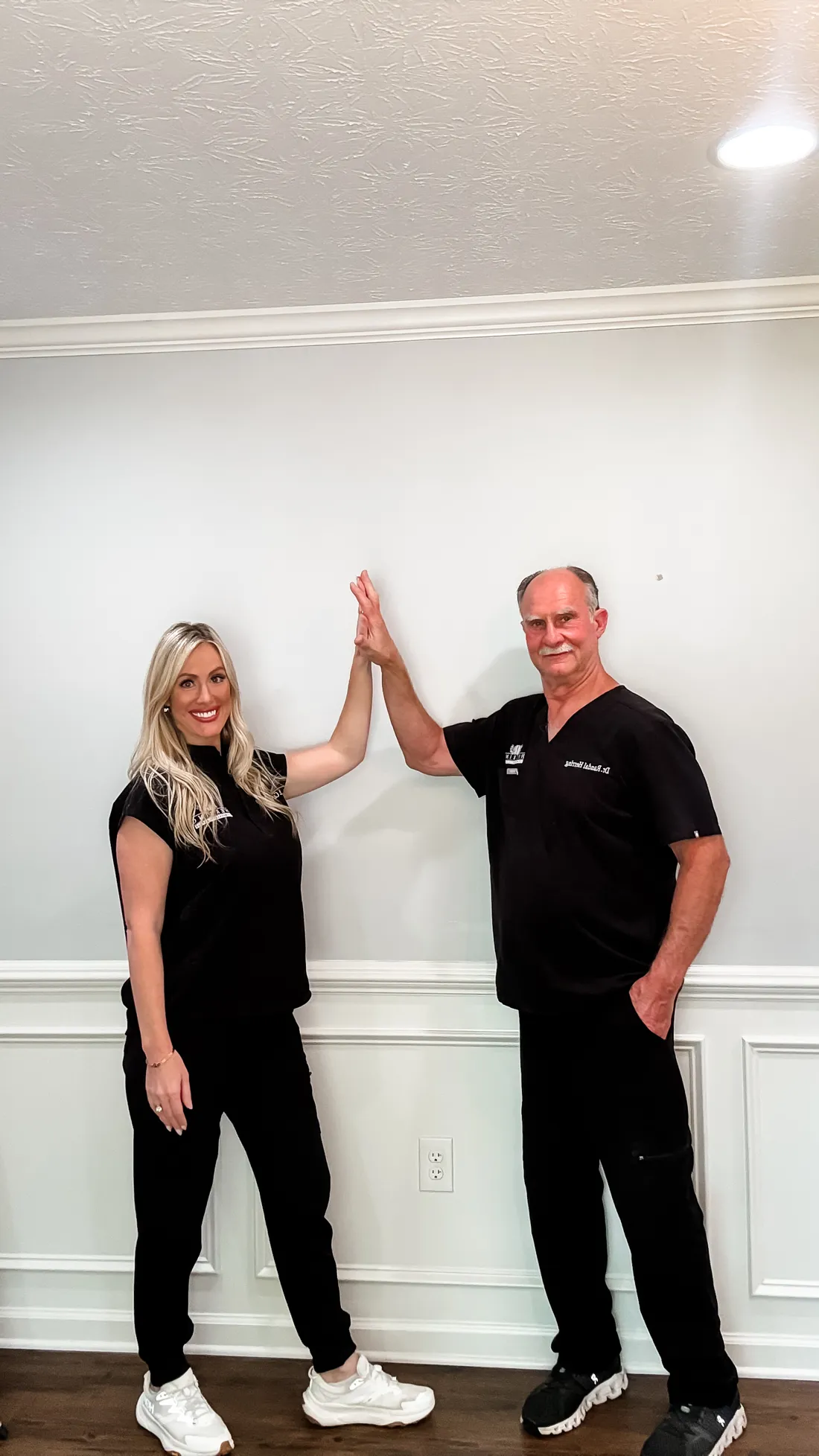 Dr. Caroline Herring and her father Dr. Randal Herring giving a high five in the clinic